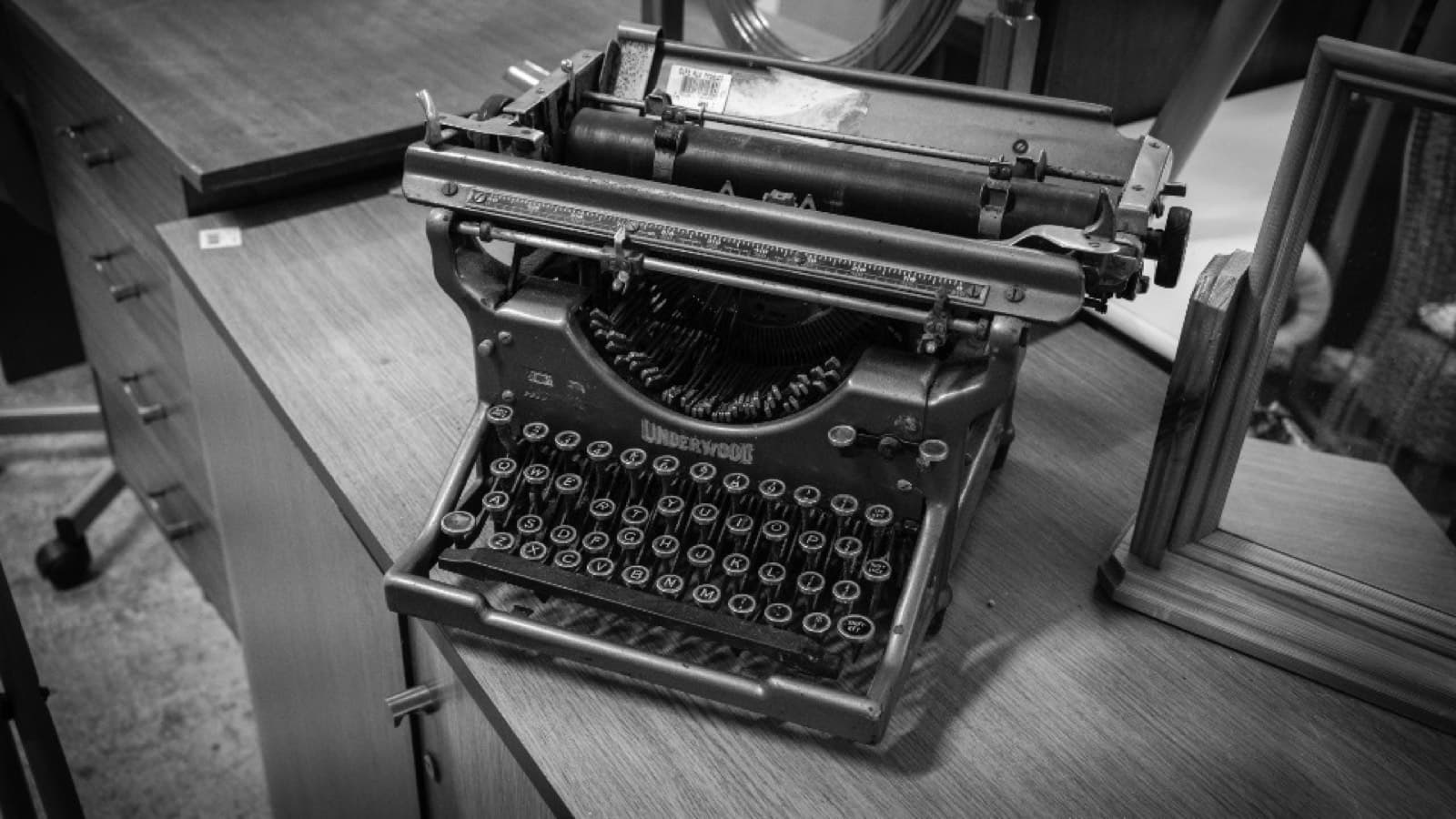 A vintage Underwood typewriter on a wooden desk, in black and white