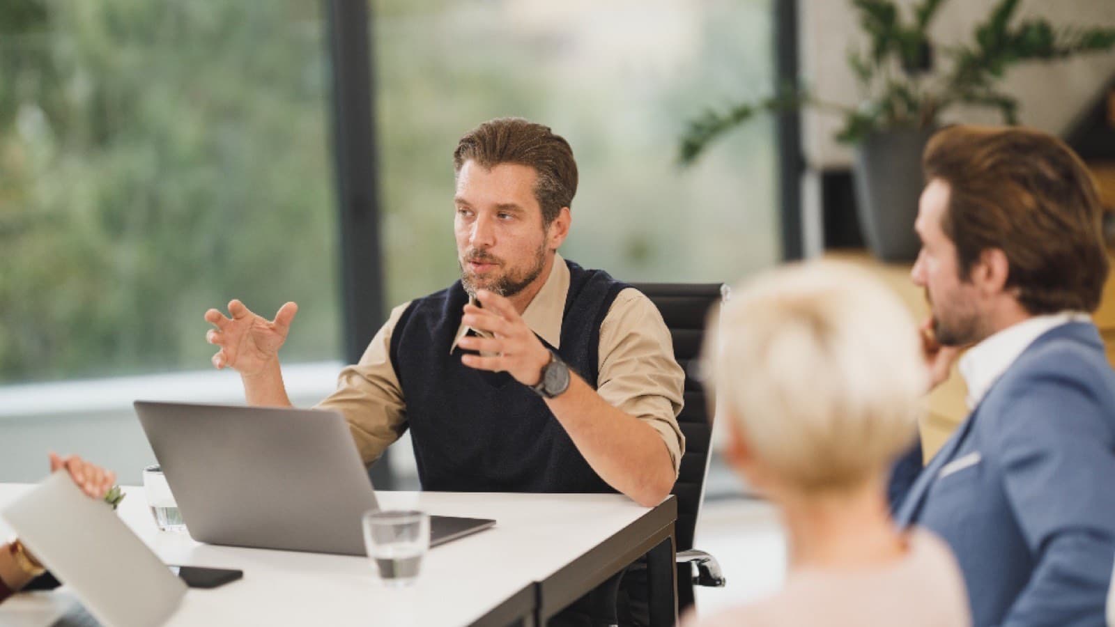 Three colleagues talking across a table, one gesturing mid-sentence