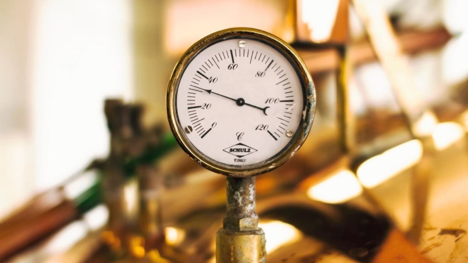 A vintage brass pressure gauge mounted on copper brewing equipment