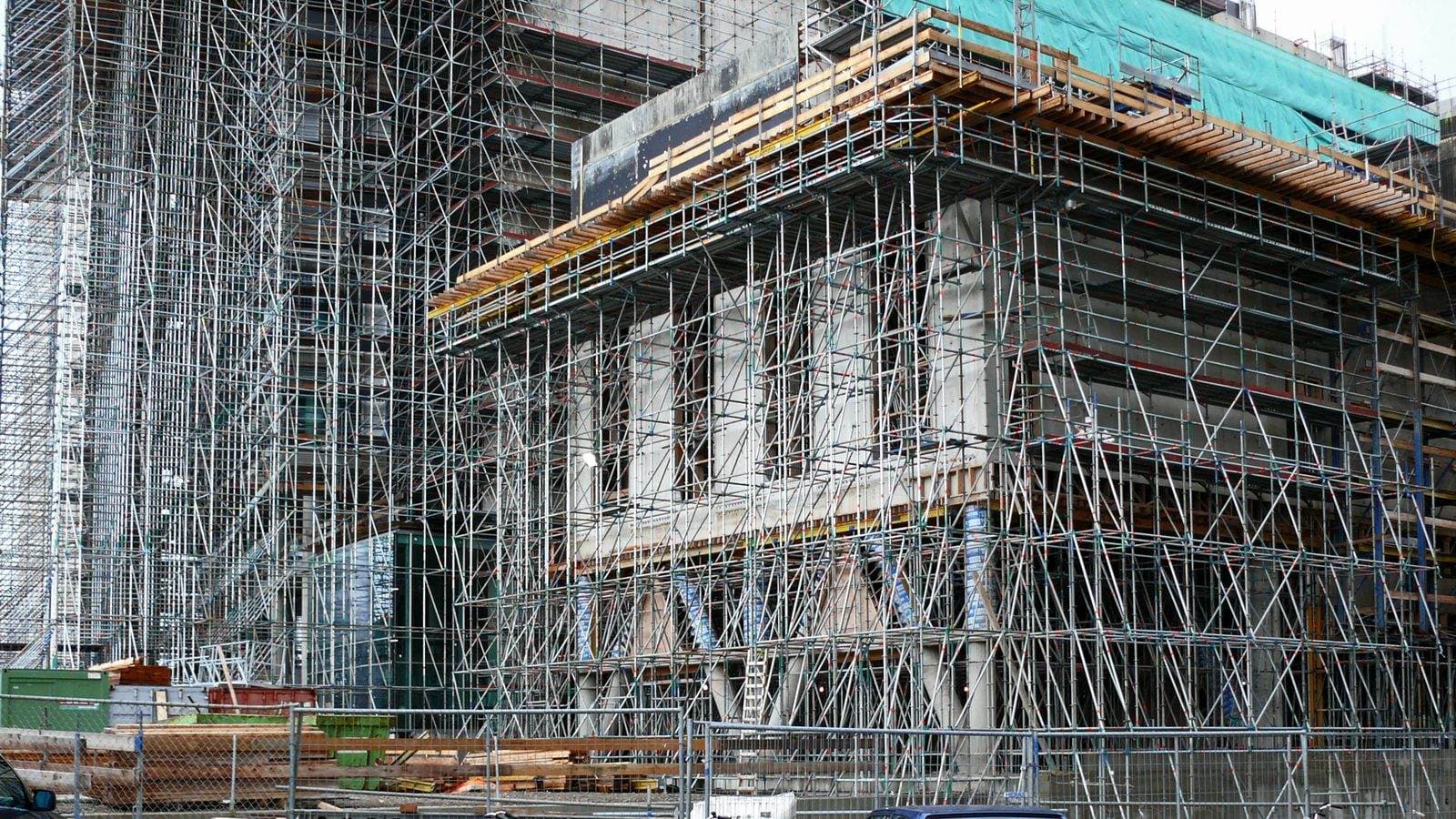 Building under construction with metal scaffolding and safety netting