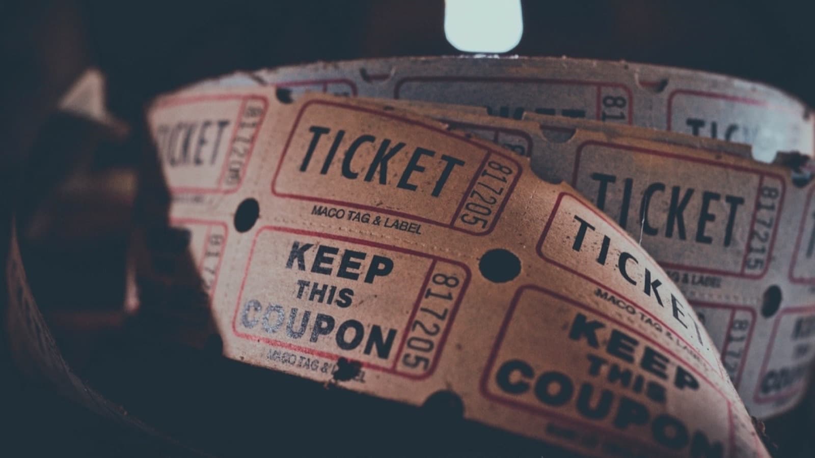 A roll of numbered paper raffle tickets unspooling in dim light