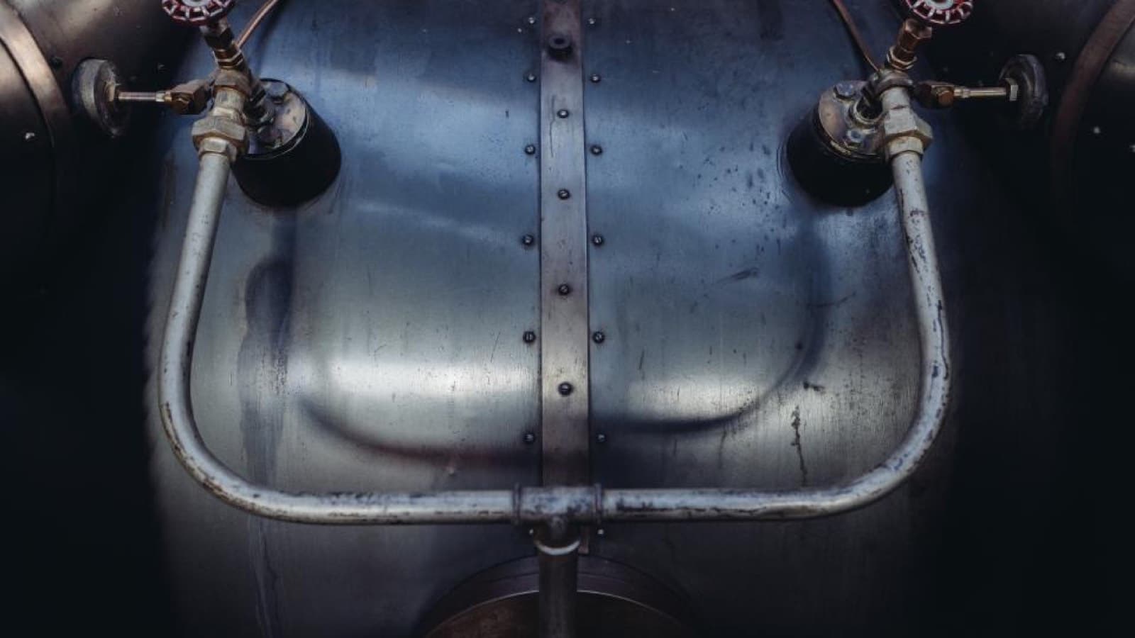 Two valve wheels and pipework on the side of an industrial steel tank